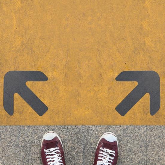 To skosnuder foran to pile i gulvet, der peger hver sin vej