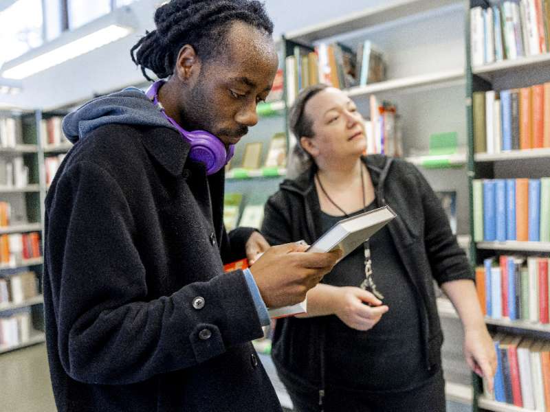 Bibliotekar hjælper studerende med at finde bøger