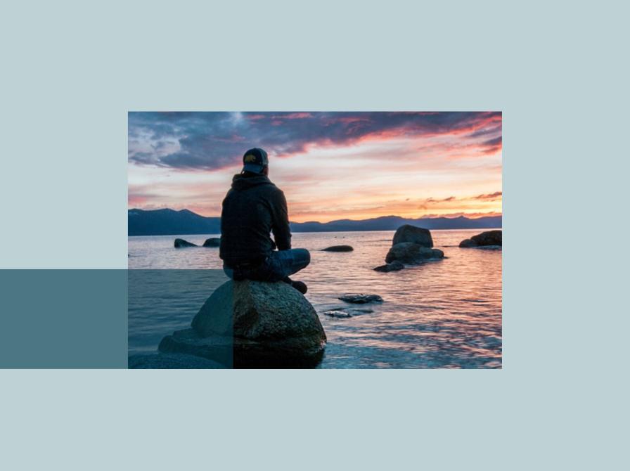 Foto af en person, som sidder på en sten i havet og mediterer